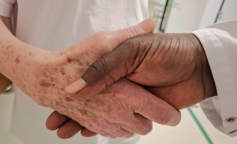 Hände von Kamillianer Priester der Delegation Benin Togo in Österreich und älterer Patientin in der Klinik Hietzing