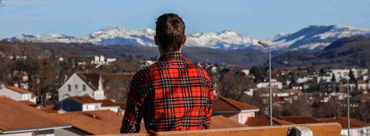 Junger Mann auf einer Bank mit Blick in die Weite symbolisiert die Suche nach Sinn und Berufung im Leben der Kamillianer