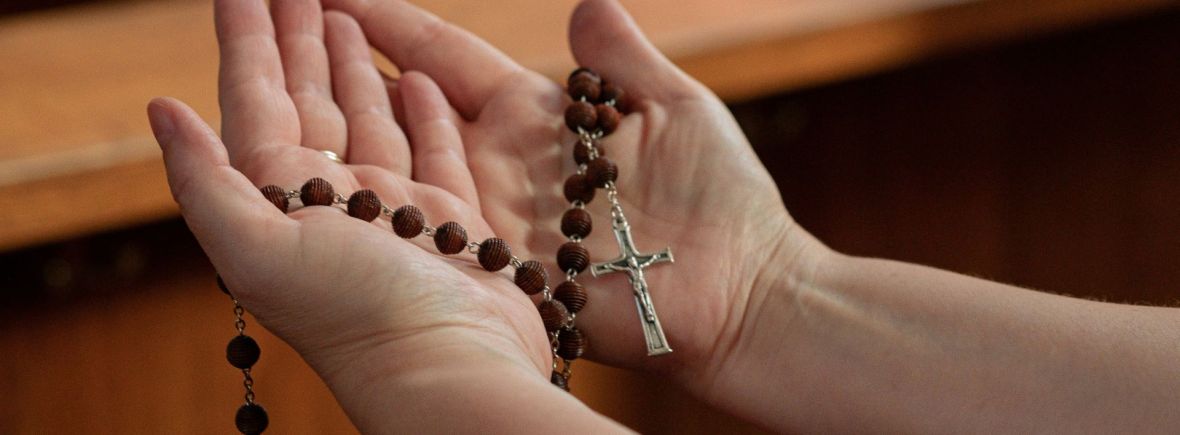 Offene Hände mit Rosenkranz im Gebet für die Anliegen der Kamillianer